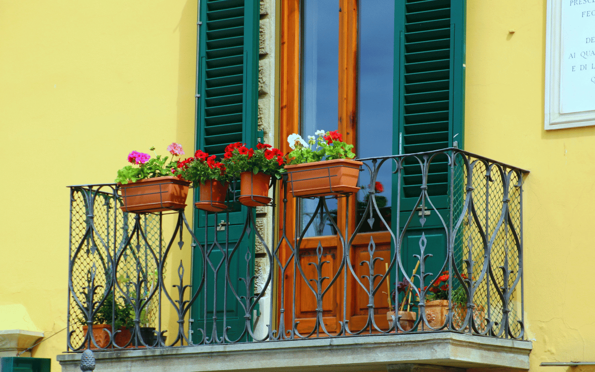 Balcón con flores y ventanas verdes